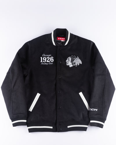 black CCM varsity jacket with Chicago Blackhawks primary logo embroidered on right chest and 1926 wordmark embroidered on left chest - front lay flat