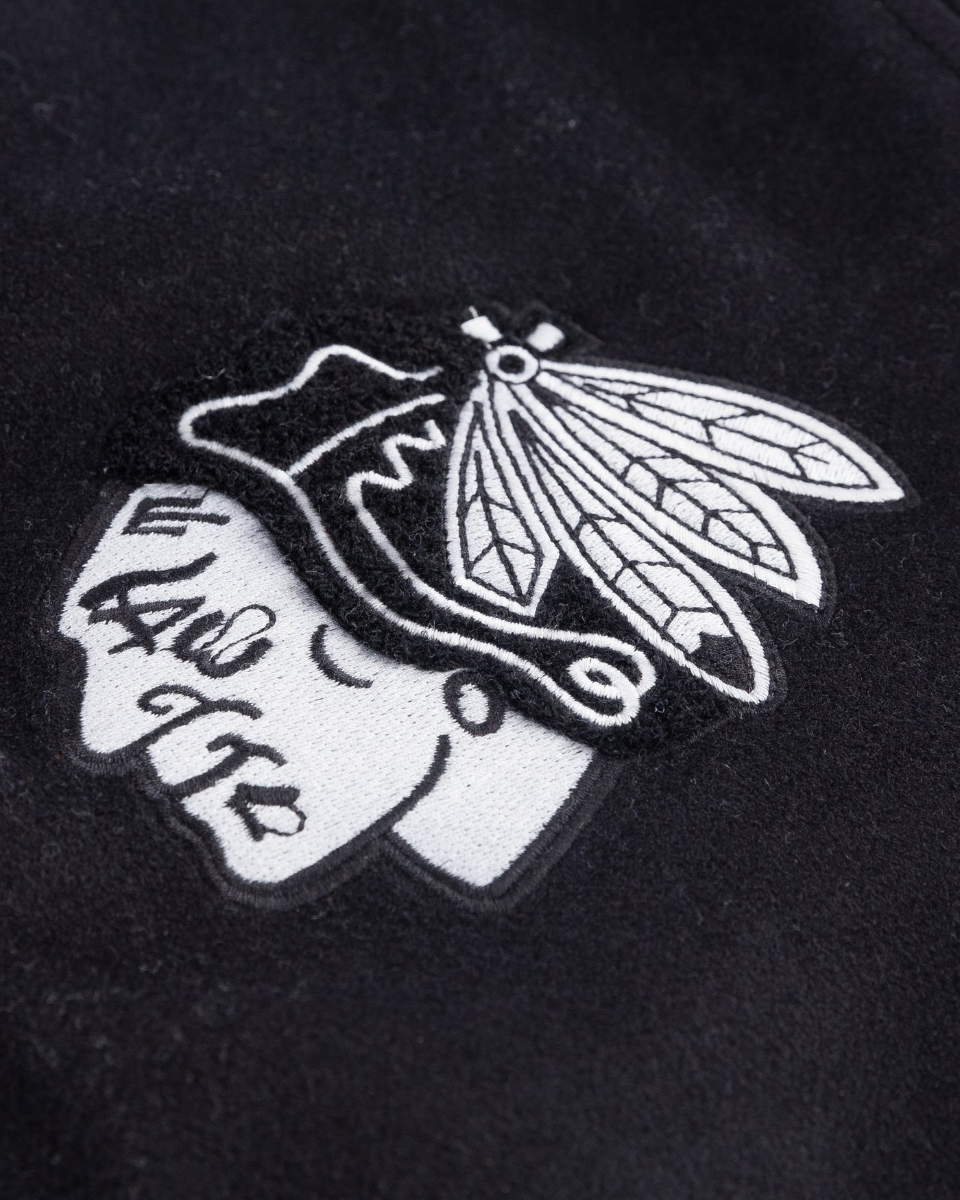 black CCM varsity jacket with Chicago Blackhawks primary logo embroidered on right chest and 1926 wordmark embroidered on left chest - detail primary logo lay flat