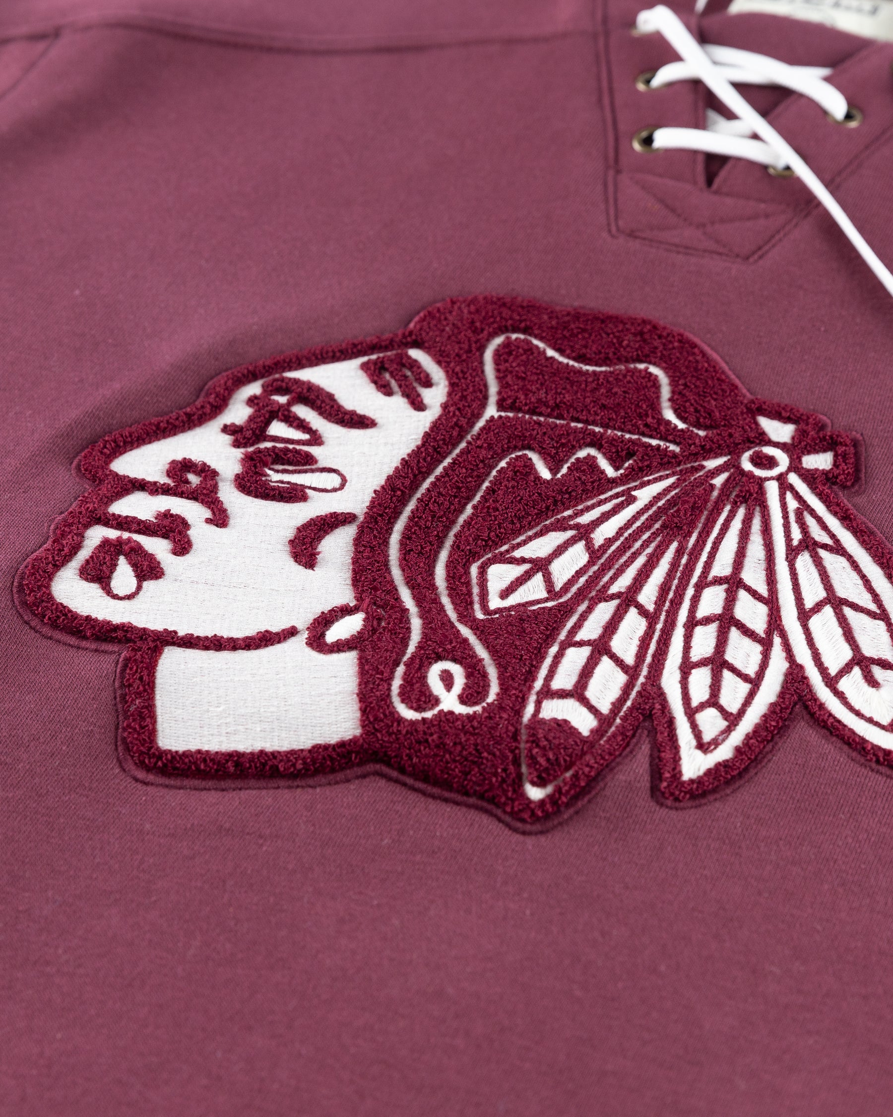 burgundy CCM lace up hoodie with hockey jersey inspired design and Chicago Blackhawks primary logo across front chest - detail lay flat