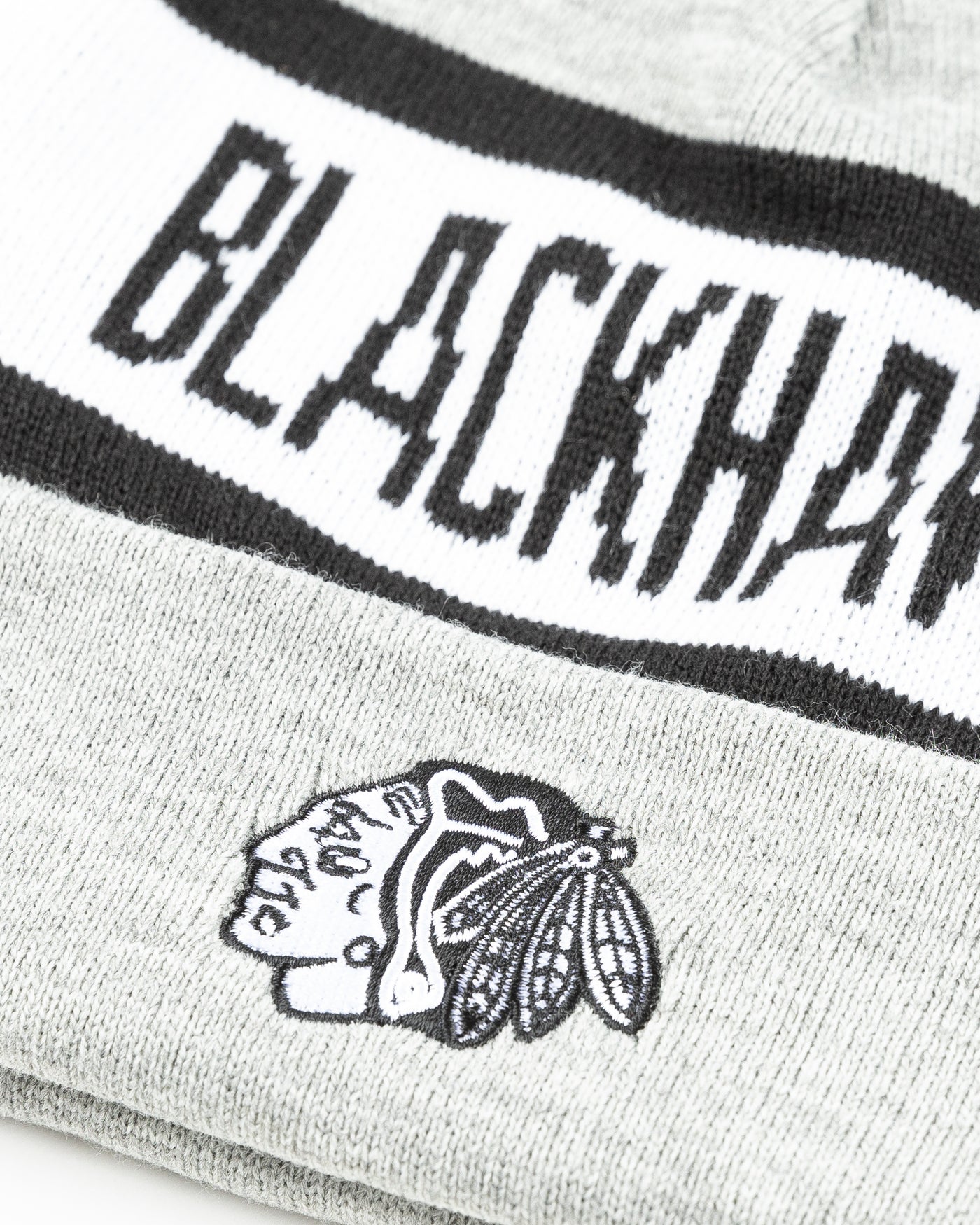 grey black and white knit beanie with Chicago Blackhawks primary logo embroidered on front and wordmark across - detail lay flat