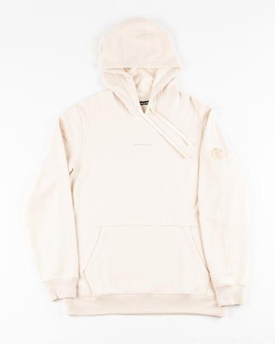 beige cream TravisMathew hoodie with tiny wordmark logo across chest and Chicago Blackhawks primary logo embroidered on left sleeve - front lay flat