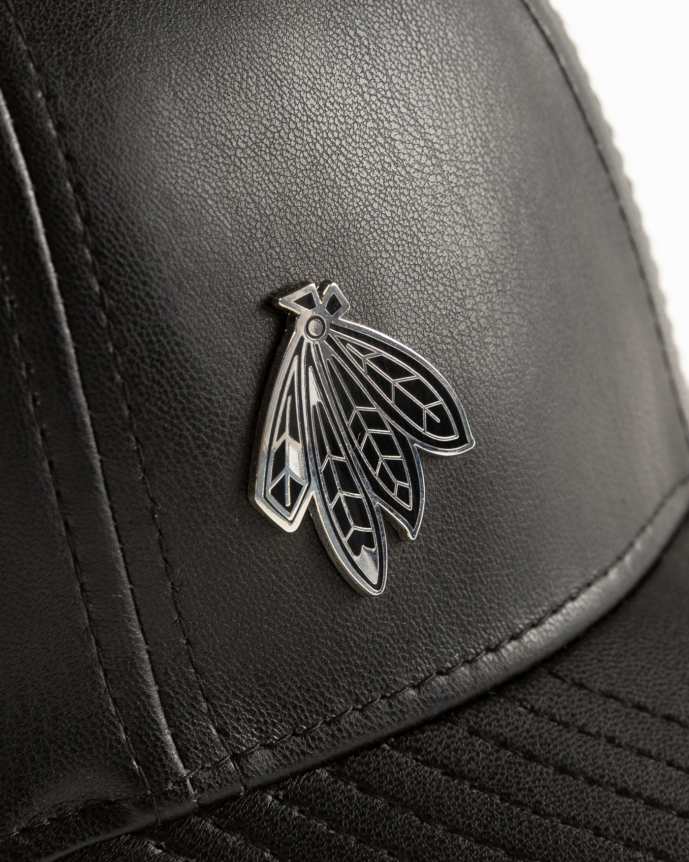black leather New Era cap with Chicago Blackhawks four feathers logo in silver pin on front - detail lay flat