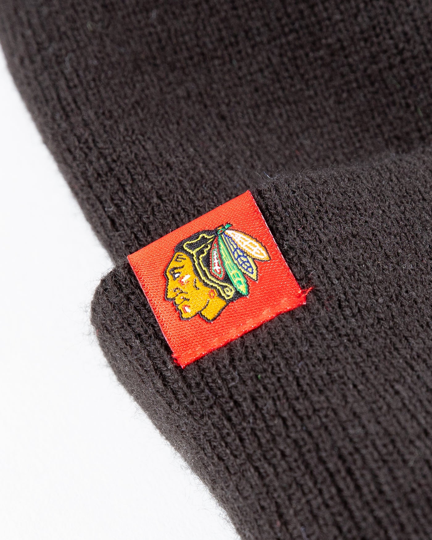 black New Era beanie lined with red satin with Chicago Blackhawks primary logo on tag on front cuff - detail logo lay flat