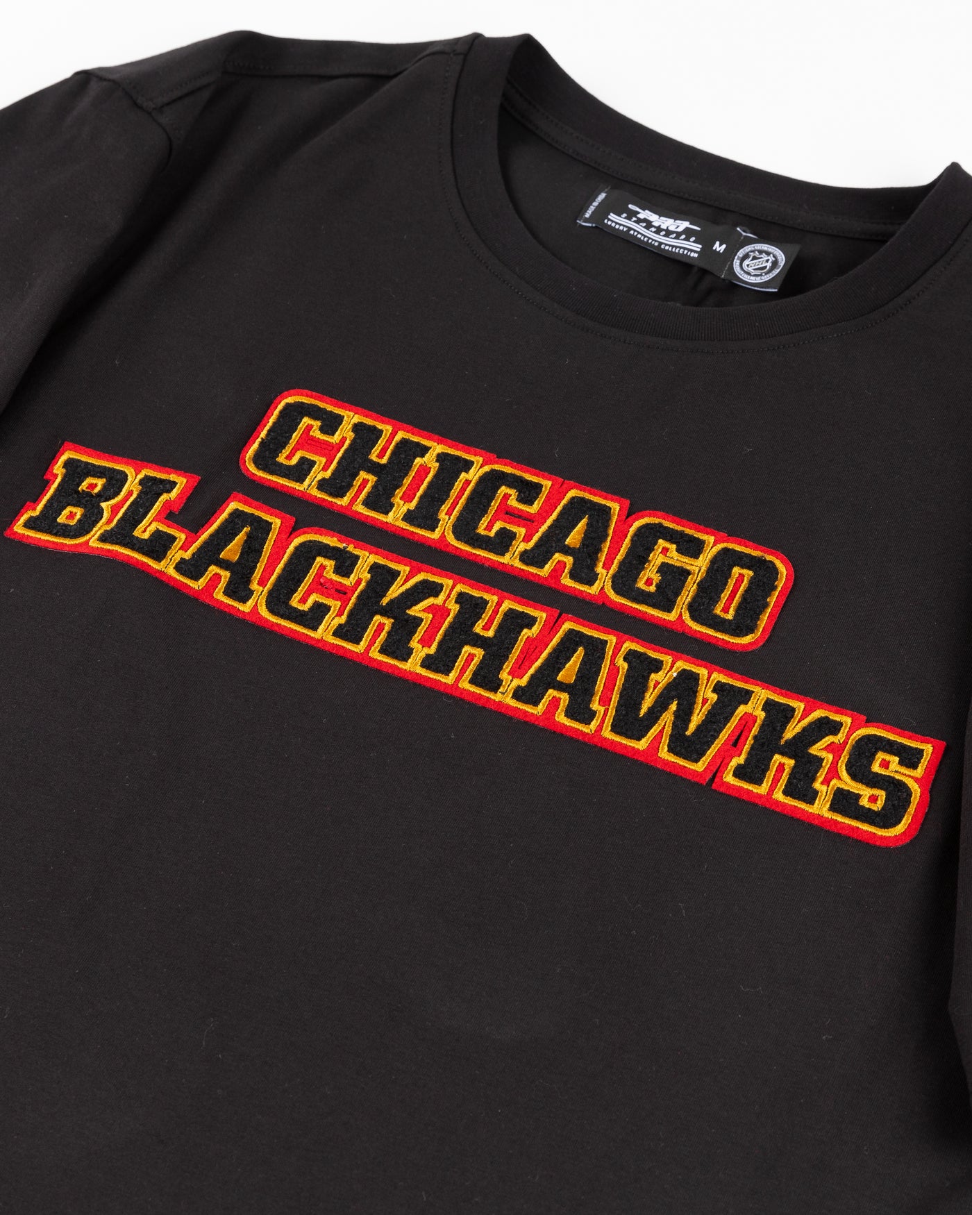 black Pro Standard tee with embroidered Chicago Blackhawks detailing on front and shoulders - front detail lay flat