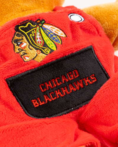 plush bear with red overalls with Chicago Blackhawks primary logo and wordmark embroidered on front - detail lay flat