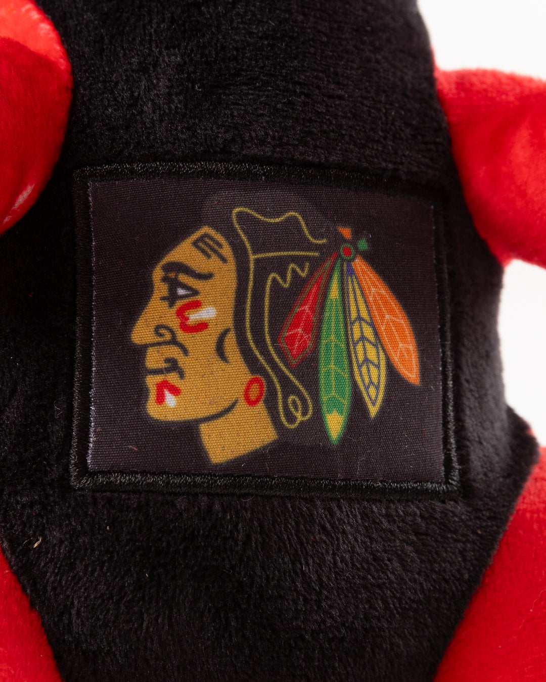 red dinosaur plush with Chicago Blackhawks primary logo on front - detail lay flat