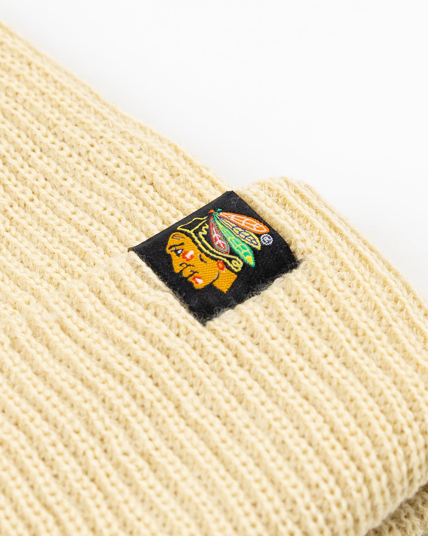 cream colored Sportiqe knit beanie with Chicago Blackhawks primary logo patch stitched on front cuff - detail lay flat