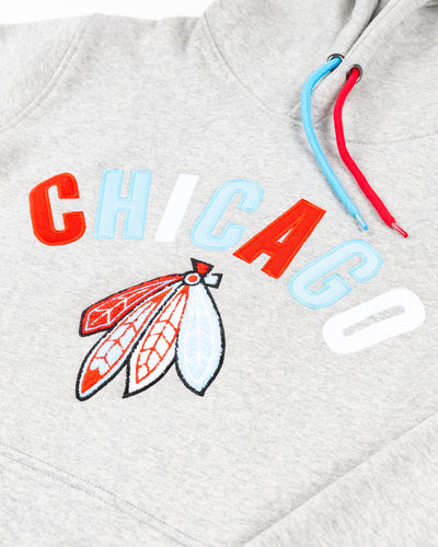 grey hoodie with Chicago wordmark and Chicago Blackhawks four feathers logo embroidered across front - detail lay flat