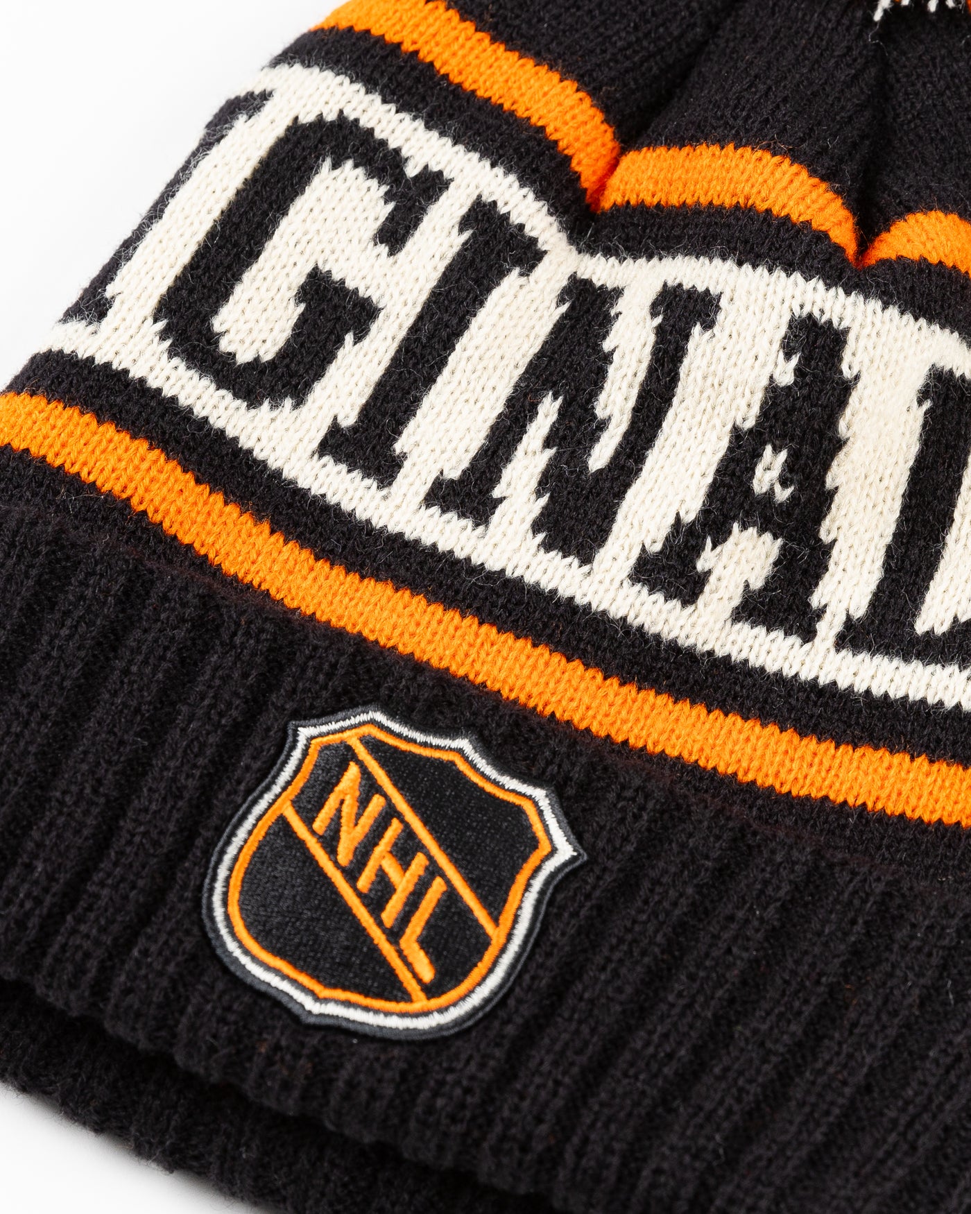 black, beige and orange knit beanie with pom with NHL patch stitched on front cuff - detailed lay flat