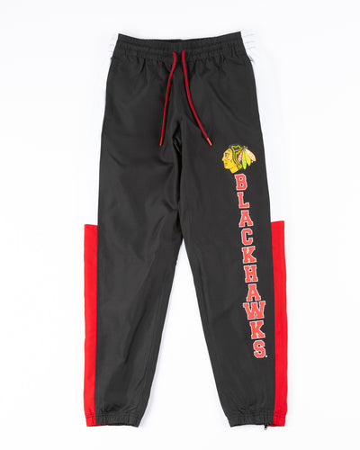 black red and white color blocked track pants with Chicago Blackhawks primary logo and wordmark on left leg - front lay flat
