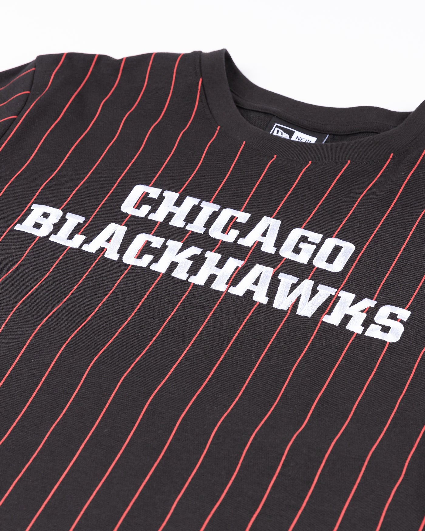 black New Era tee with red pinstripes and Chicago Blackhawks wordmark embroidered on front and primary logo printed on back - front detail lay flat