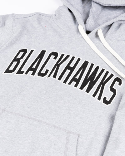 grey '47 brand hoodie with Chicago Blackhawks wordmark across chest and secondary logo on left shoulder - detail lay flat