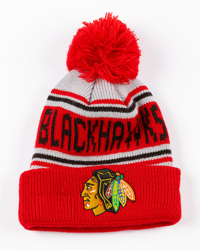 New Era knit youth beanie with pom with Chicago Blackhawks wordmark and primary logo embroidered on cuff - front lay flat