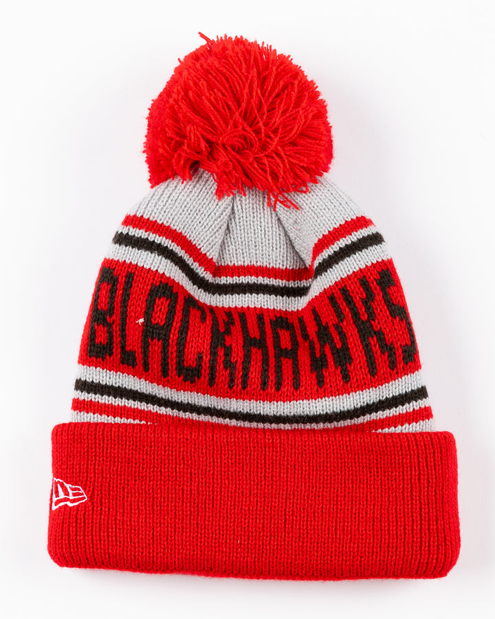 New Era knit youth beanie with pom with Chicago Blackhawks wordmark and primary logo embroidered on cuff - back lay flat