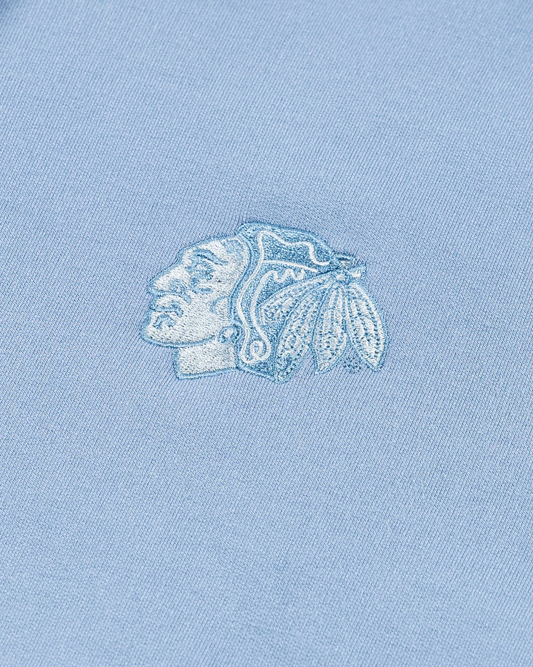 light blue TravisMathew hoodie with Chicago Blackhawks tonal primary logo embroidered on left chest - detail lay flat