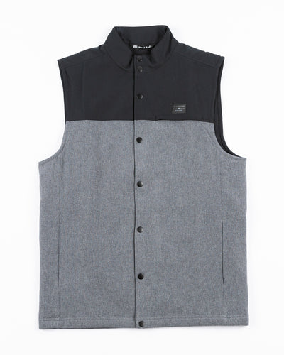 two tone black and grey TravisMathew vest with Chicago Blackhawks primary logo embroidered on back yoke - front lay flat