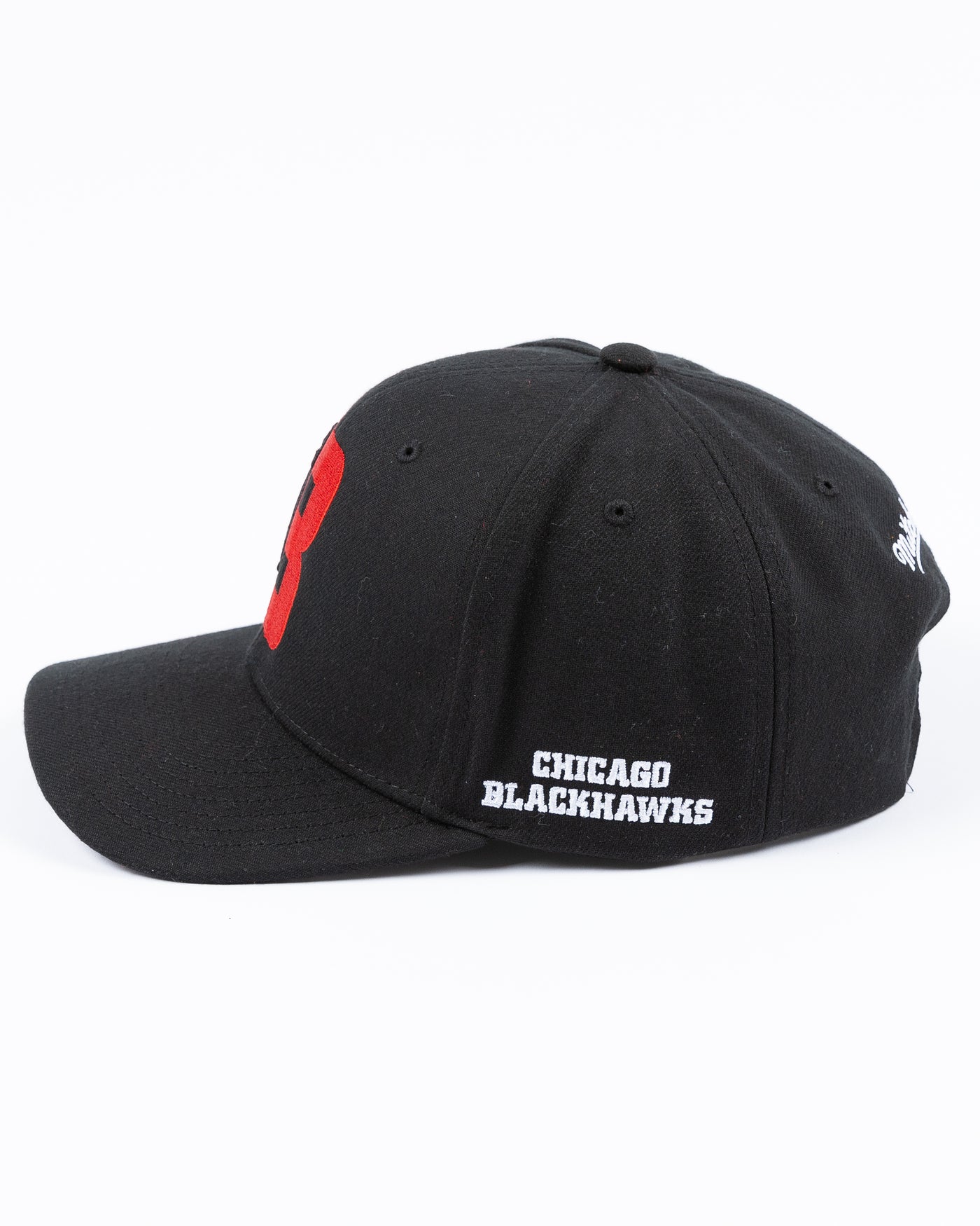 black Mitchell & Ness snapback with Chicago Blackhawks four feathers logo embroidered on red letter B - left side lay flat