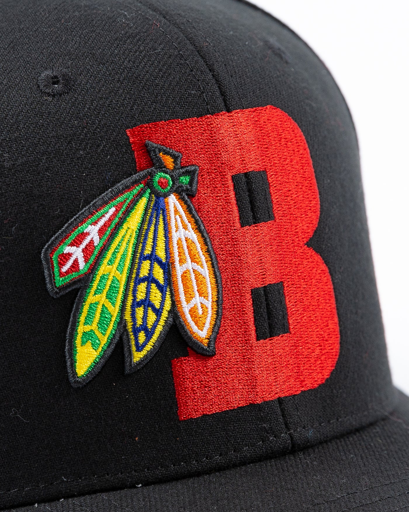 black Mitchell & Ness snapback with Chicago Blackhawks four feathers logo embroidered on red letter B - detail lay flat