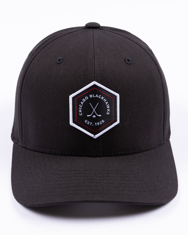 black TravisMathew adjustable cap with hexagon patch on front and Chicago Blackhawks wordmark and crossed hockey sticks graphic - front lay flat