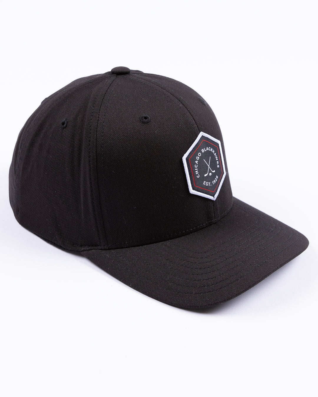 black TravisMathew adjustable cap with hexagon patch on front and Chicago Blackhawks wordmark and crossed hockey sticks graphic - right angle lay flat