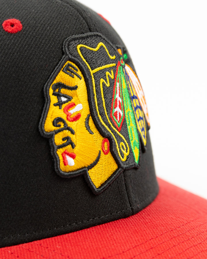 black and red Mitchell & Ness snapback with Chicago Blackhawks primary logo on front, secondary logo on left side and wordmark Chicago on right - front detail lay flat