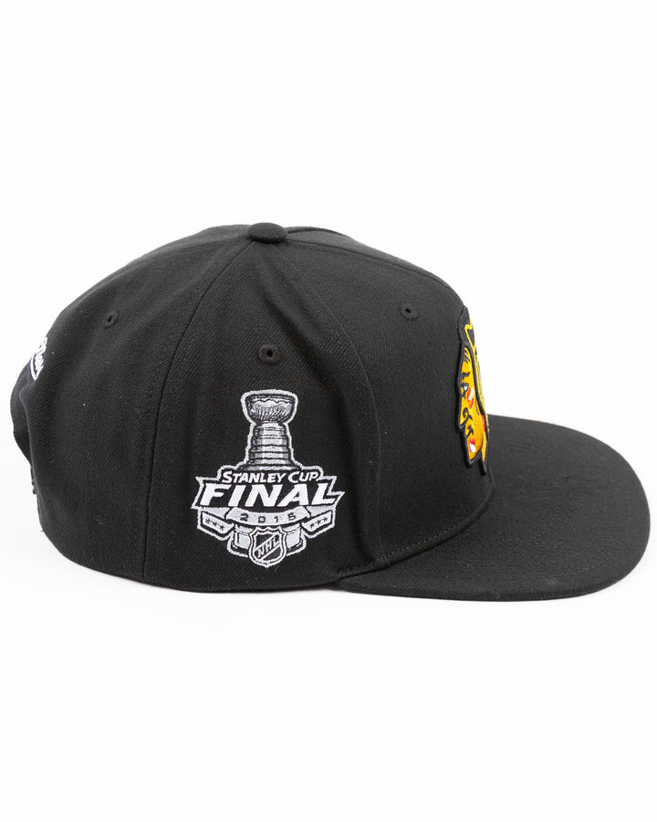 black Mitchell & Ness snapback cap with Chicago Blackhawks primary logo embroidered on front and 2015 Stanley Cup championship patch on right side - right side lay flat