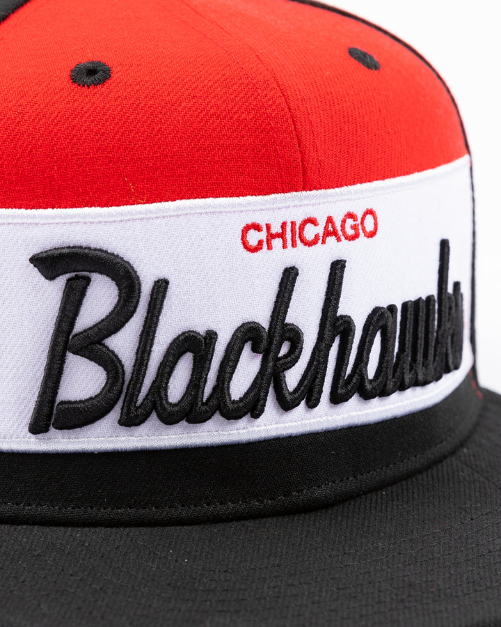 black white and red Mitchell & Ness snapback cap with Chicago Blackhawks wordmark on front and primary logo on right side - front detail lay flat