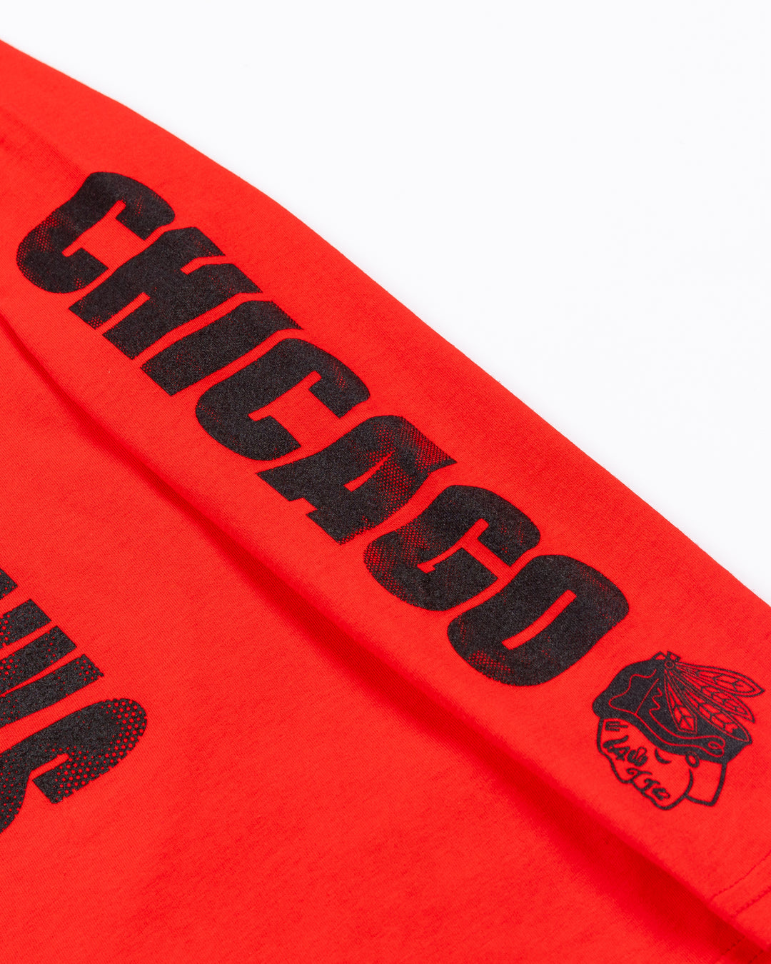 red youth long sleeve tee with Chicago Blackhawks wordmark and helmet graphic on front and Chicago wordmark on left arm - arm detail lay flat