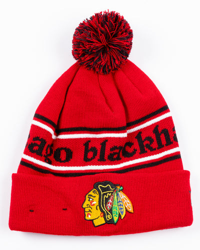 red New Era beanie with two tone pom and Chicago Blackhawks wordmark across front and embroidered primary logo on front cuff - front lay flat