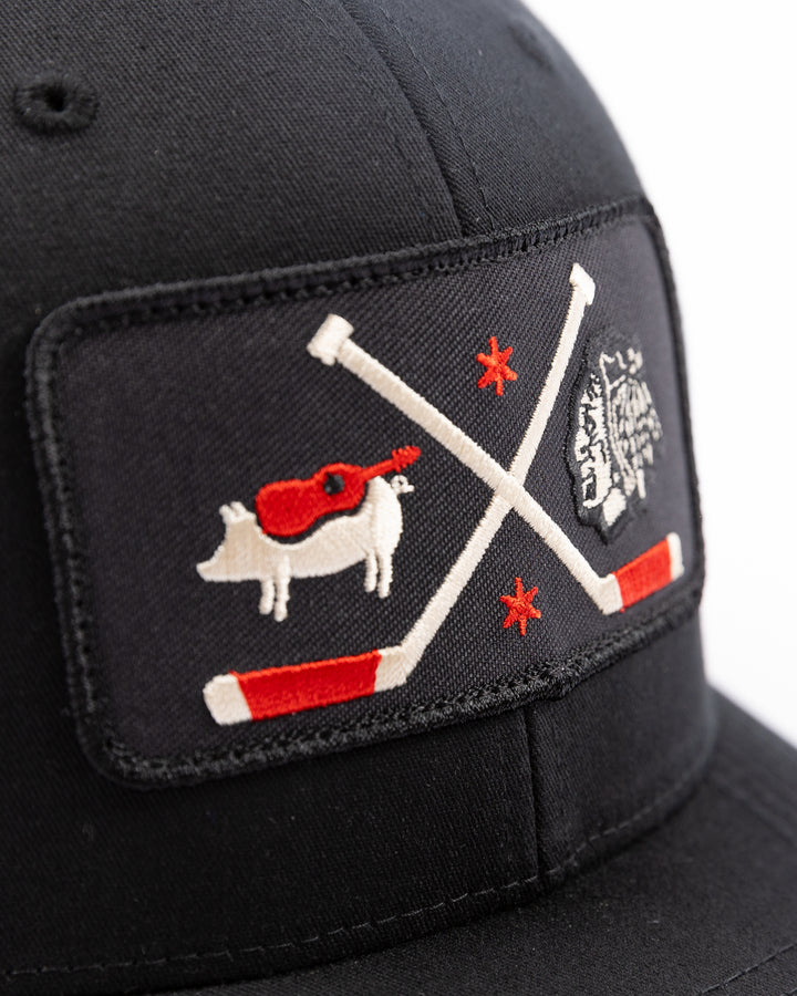 black trucker hat with patch of Windy City Smokeout logo and Chicago Blackhawks primary logo on front - detail lay flat