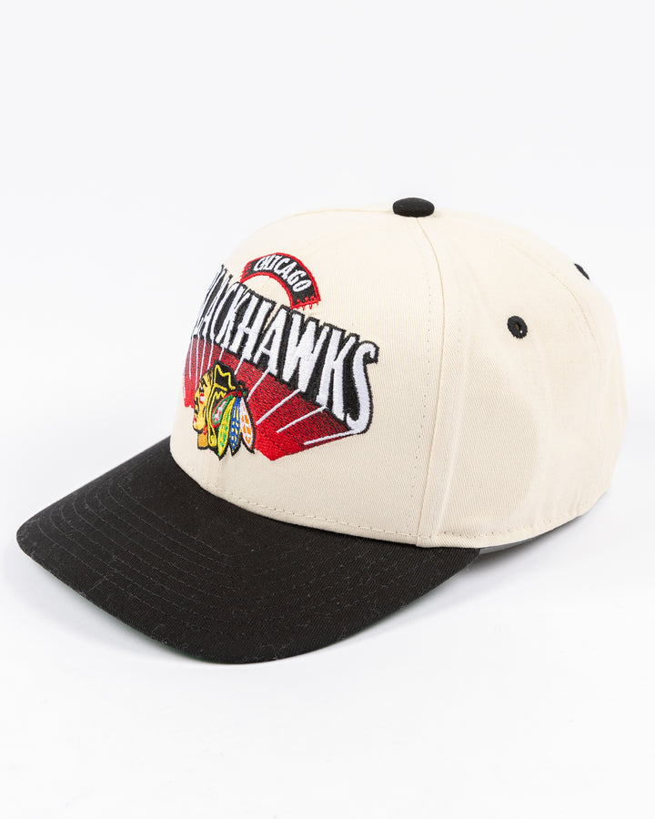 youth cream and black Mitchell & Ness snapback cap with Chicago Blackhawks wordmark and primary logo on front - left angle lay flat