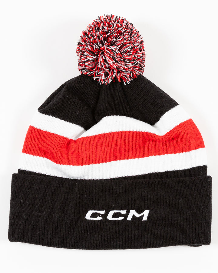 black CCM knit beanie with red and white stripe on front and embroidered Blackhawks Hockey wordmark on front cuff with multicolor pom on top - back lay flat