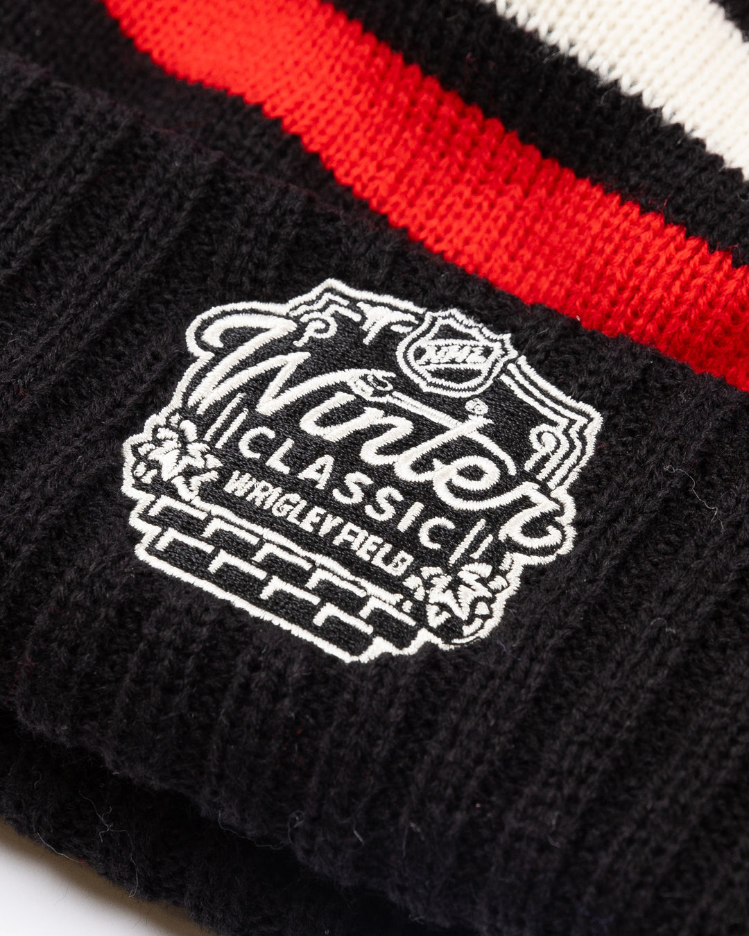 striped black white and red American Needle pom knit hat with multi color pom on top and Chicago Blackhawks and NHL Winter Classic patches embroidered on front and back - back lay flat