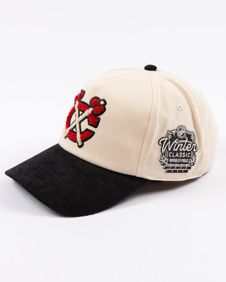 two tone ivory and black American Needle adjustable snapback hat with chenille Chicago Blackhawks secondary logo and Winter Classic logo embroidered on left side - left angle lay flat