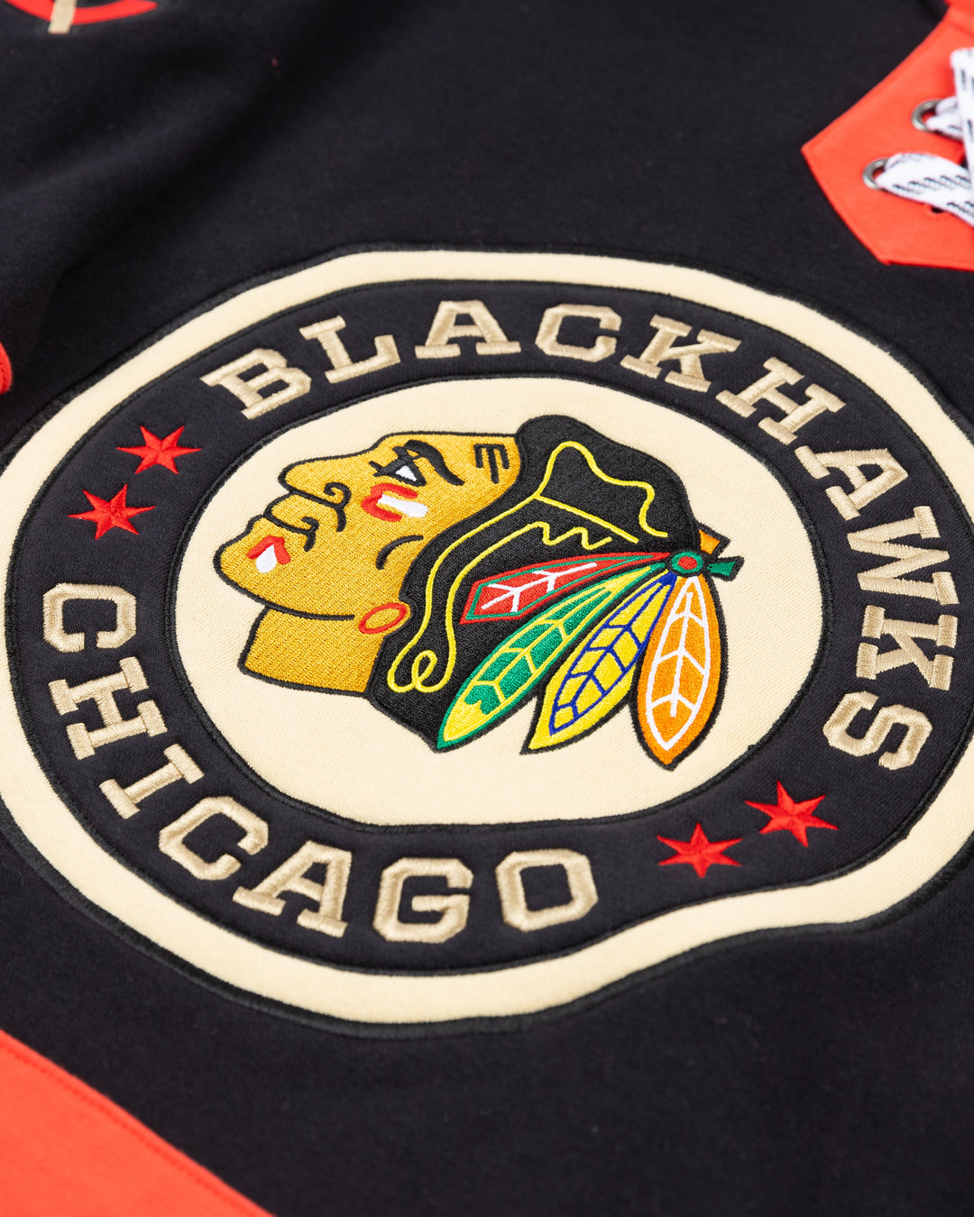 black Mitchell & Ness lace up crewneck with Chicago Blackhawks Winter Classic embroidered patches on front and shoulders - front detail lay flat