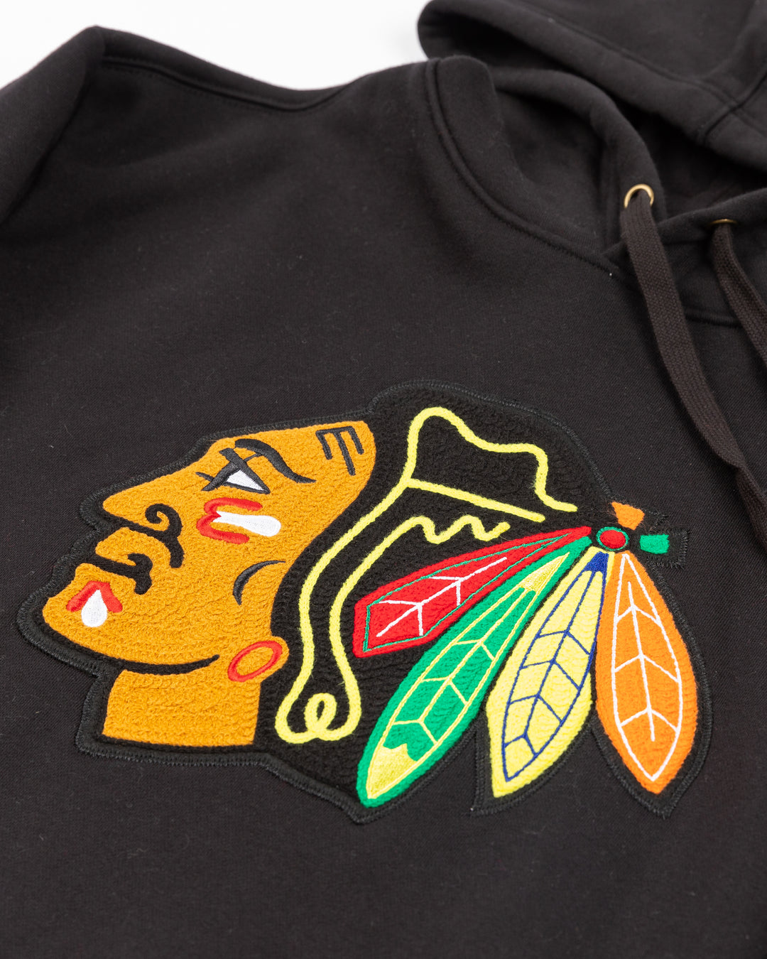 black Mitchell & Ness hoodie with chainstitch Chicago Blackhawks primary logo on front and ribbed cuffs - front detail lay flat