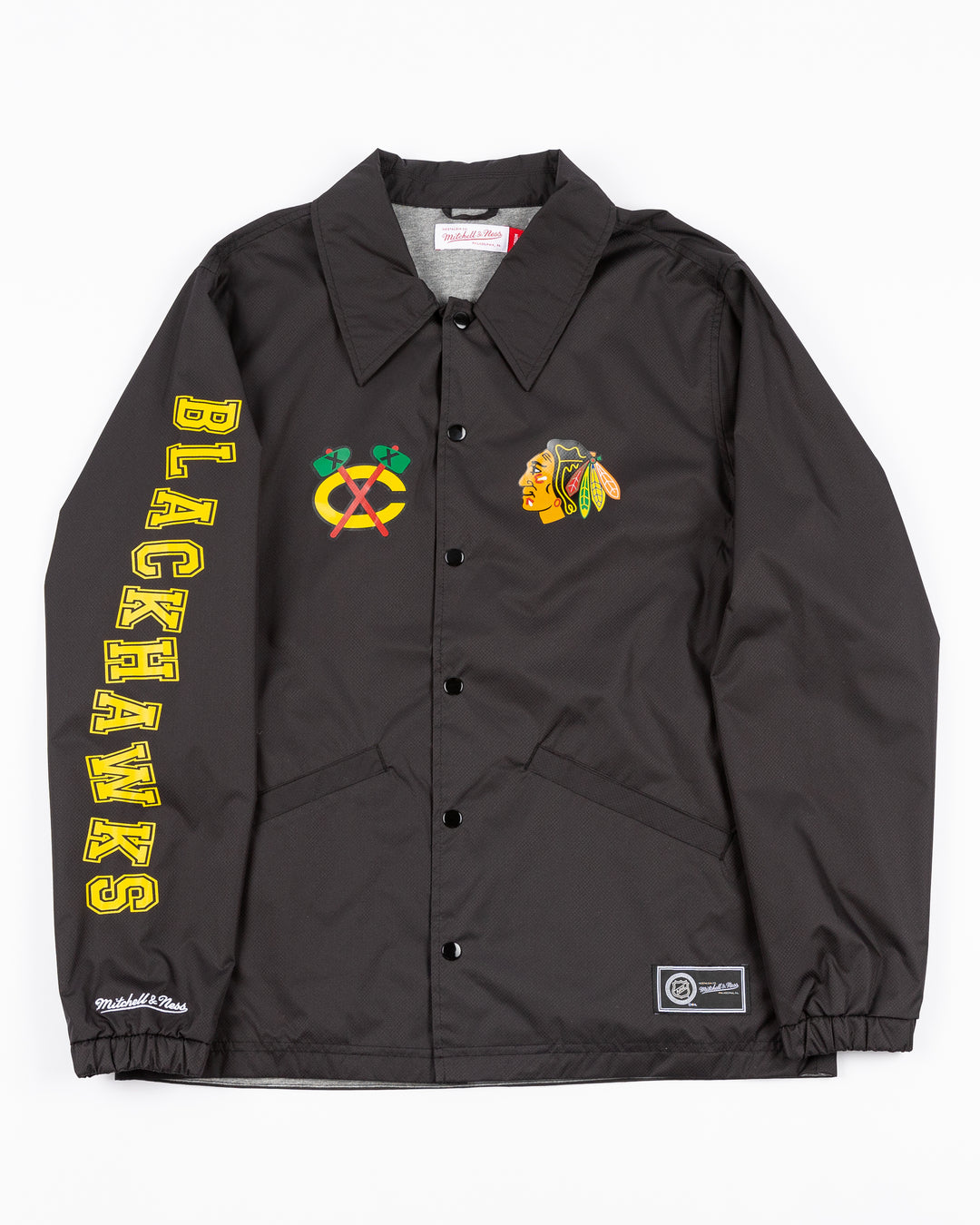 black Mitchell & Ness coaches jacket with Chicago Blackhawks secondary logo on right chest and primary logo on left chest and wordmark down right sleeve - front lay flat