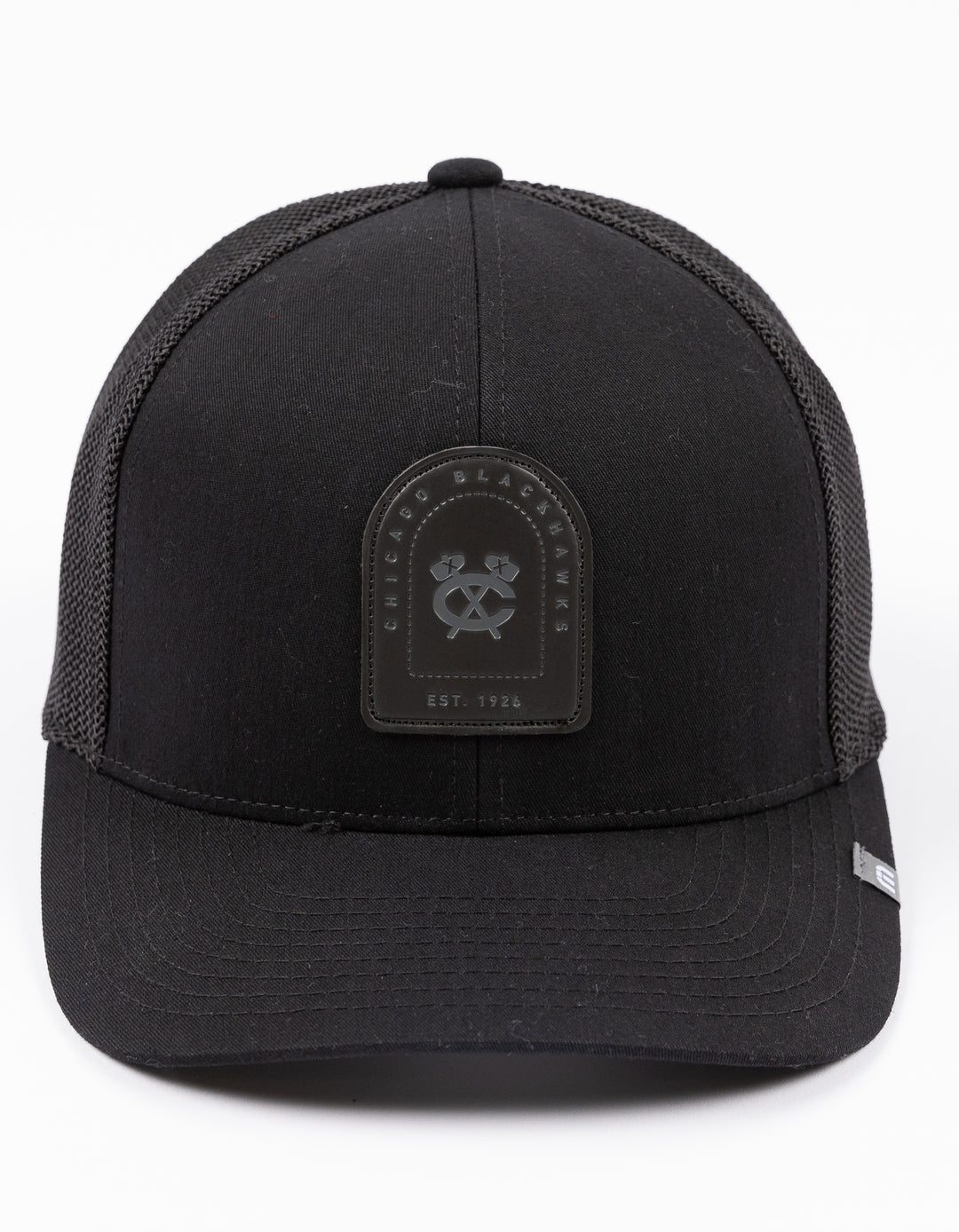 black adjustable TravisMatthew trucker hat with leather patch on front with Chicago Blackhawks secondary logo and wordmark on front - front lay flat