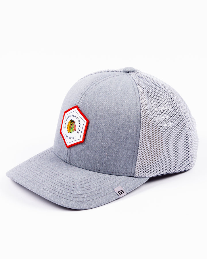 heather grey TravisMathew adjustable trucker cap with hexagon patch on front with Chicago Blackhawks primary logo and wordmark - left angle lay flat