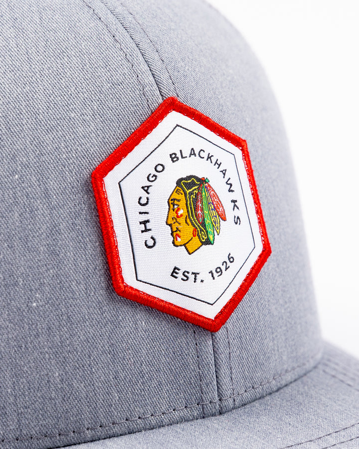 heather grey TravisMathew adjustable trucker cap with hexagon patch on front with Chicago Blackhawks primary logo and wordmark - front detail lay flat