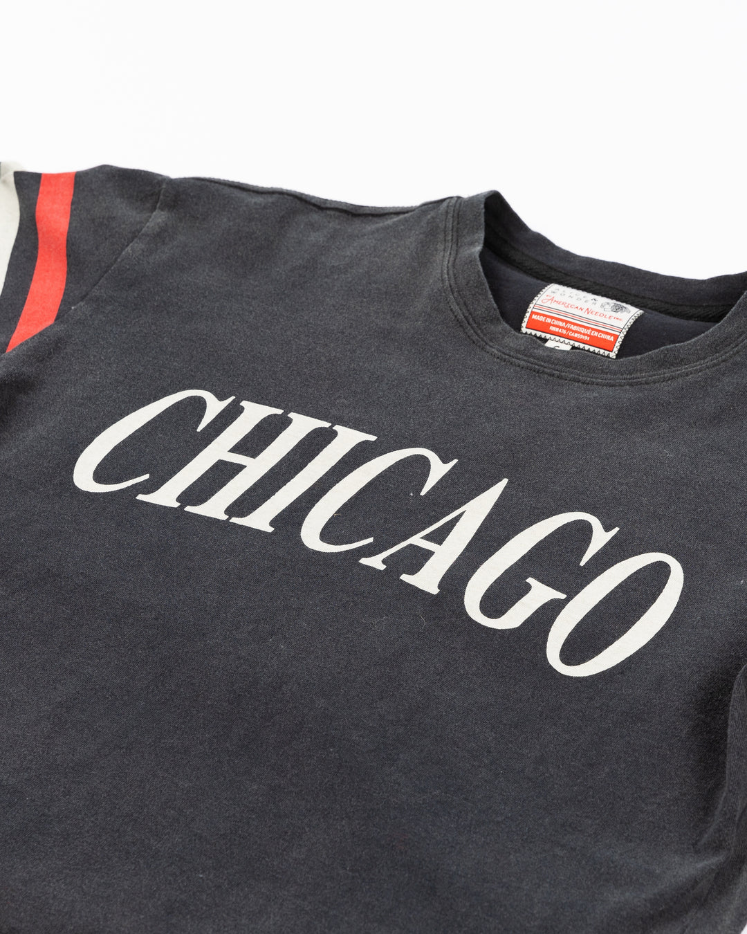 black cropped Alice & Wonder tee with Chicago wordmark graphic across front and Chicago Blackhawks primary logo on shoulder with jersey-inspired stripes on right sleeve - front detail lay flat