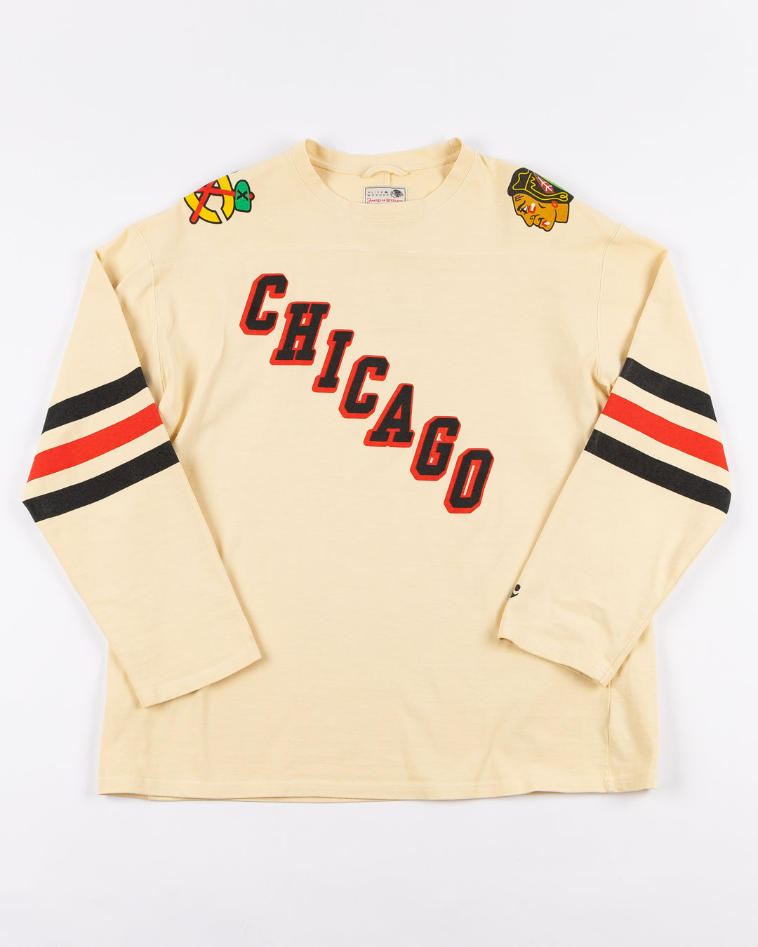 cream Alice & Wonder long sleeve tee with diagonal Chicago wordmark graphic and Chicago Blackhawks secondary and primary logo on shoulders with jersey stripes on sleeves - front lay flat