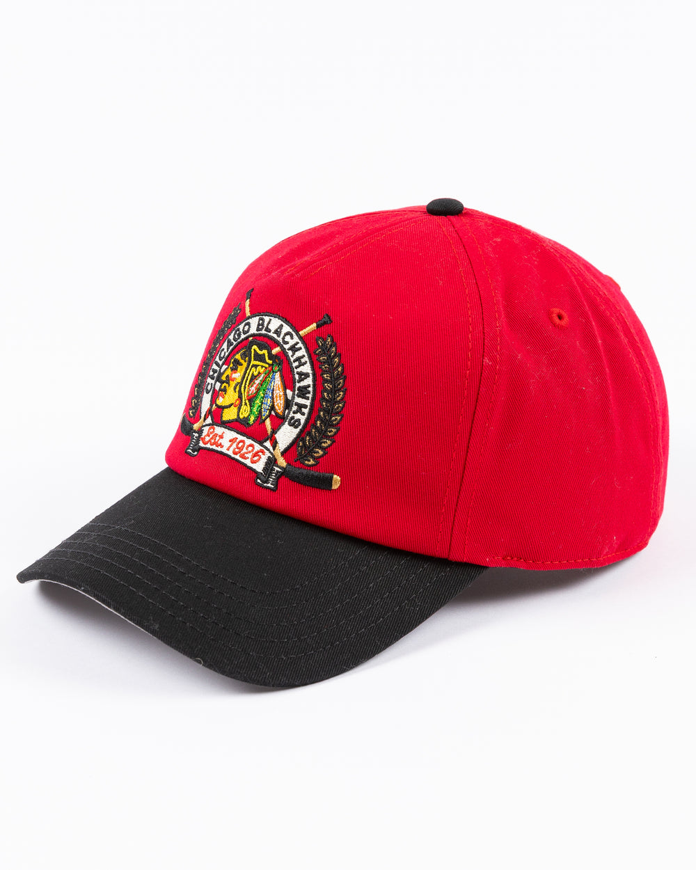 American Needle adjustable two tone red and black hat with Chicago Blackhawks primary logo and two crossed hockey sticks embroidered on front - left angle lay flat