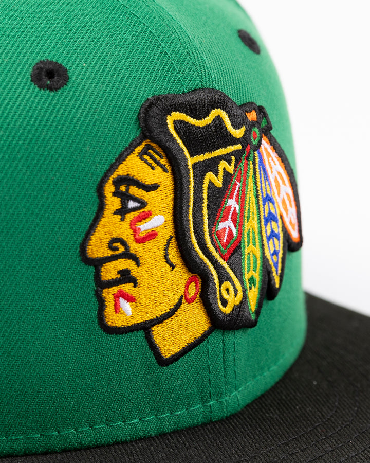 green and black New Era 9FIFTY snapback with Chicago Blackhawks primary logo embroidered on front and black and white star pattern on bottom brim - front detail lay flat