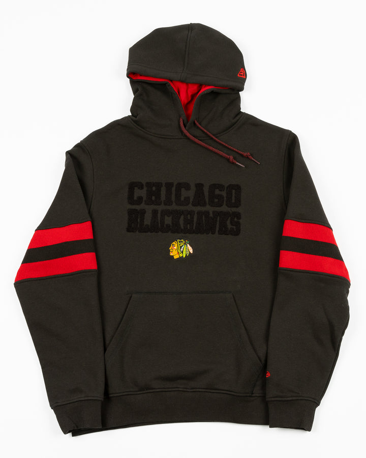 black New Era hoodie with Chicago Blackhawks chenille word graphic on front above embroidered primary logo with red stripes on sleeves - front lay flat