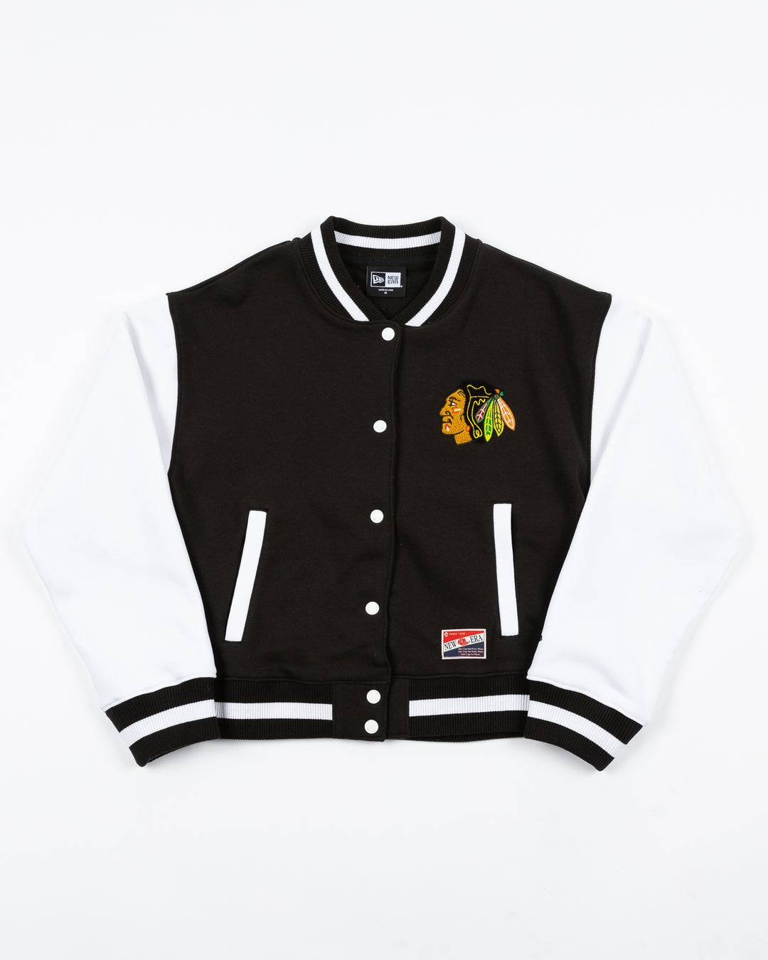 black and white ladies New Era varsity jacket with Chicago Blackhawks primary logo on left chest and Blackhawks wordmark on back - front lay flat