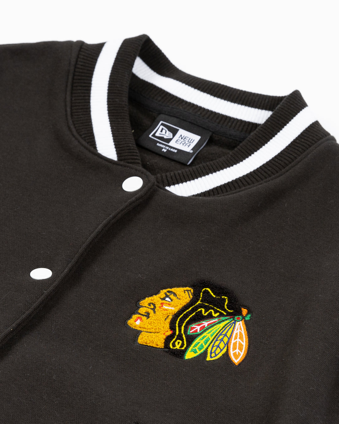 black and white ladies New Era varsity jacket with Chicago Blackhawks primary logo on left chest and Blackhawks wordmark on back - front detail lay flat