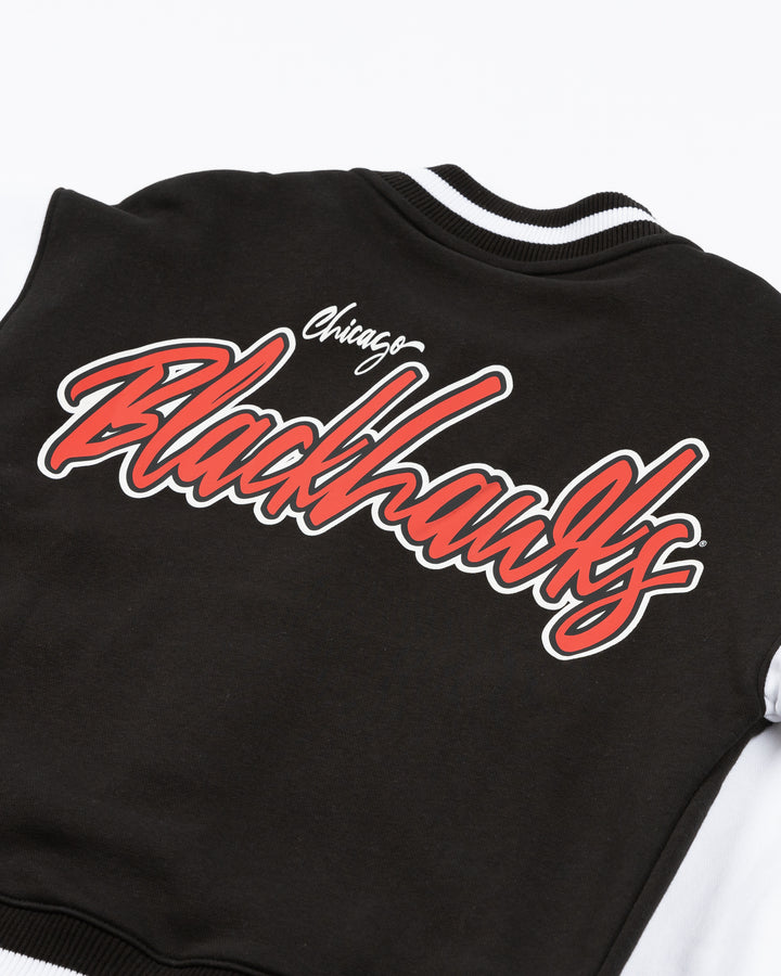 black and white ladies New Era varsity jacket with Chicago Blackhawks primary logo on left chest and Blackhawks wordmark on back - back lay flat