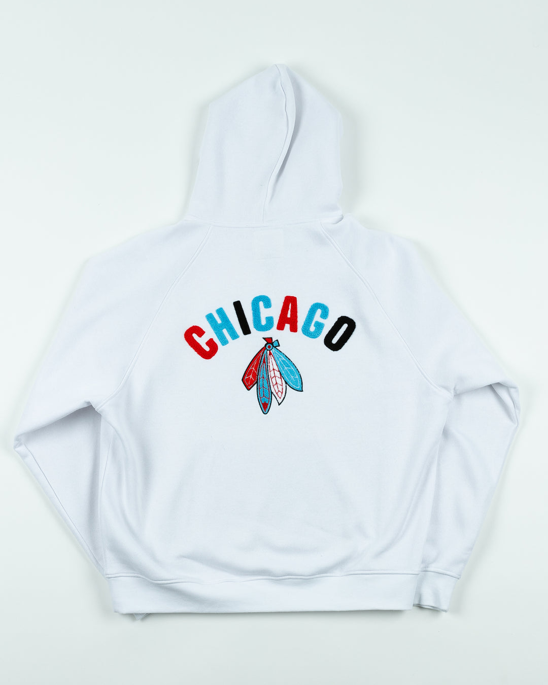 white oversized hoodie with Chicago Blackhawks secondary logo embroidered on front chest and Chicago wordmark and four feathers logo embroidered on back - back lay flat