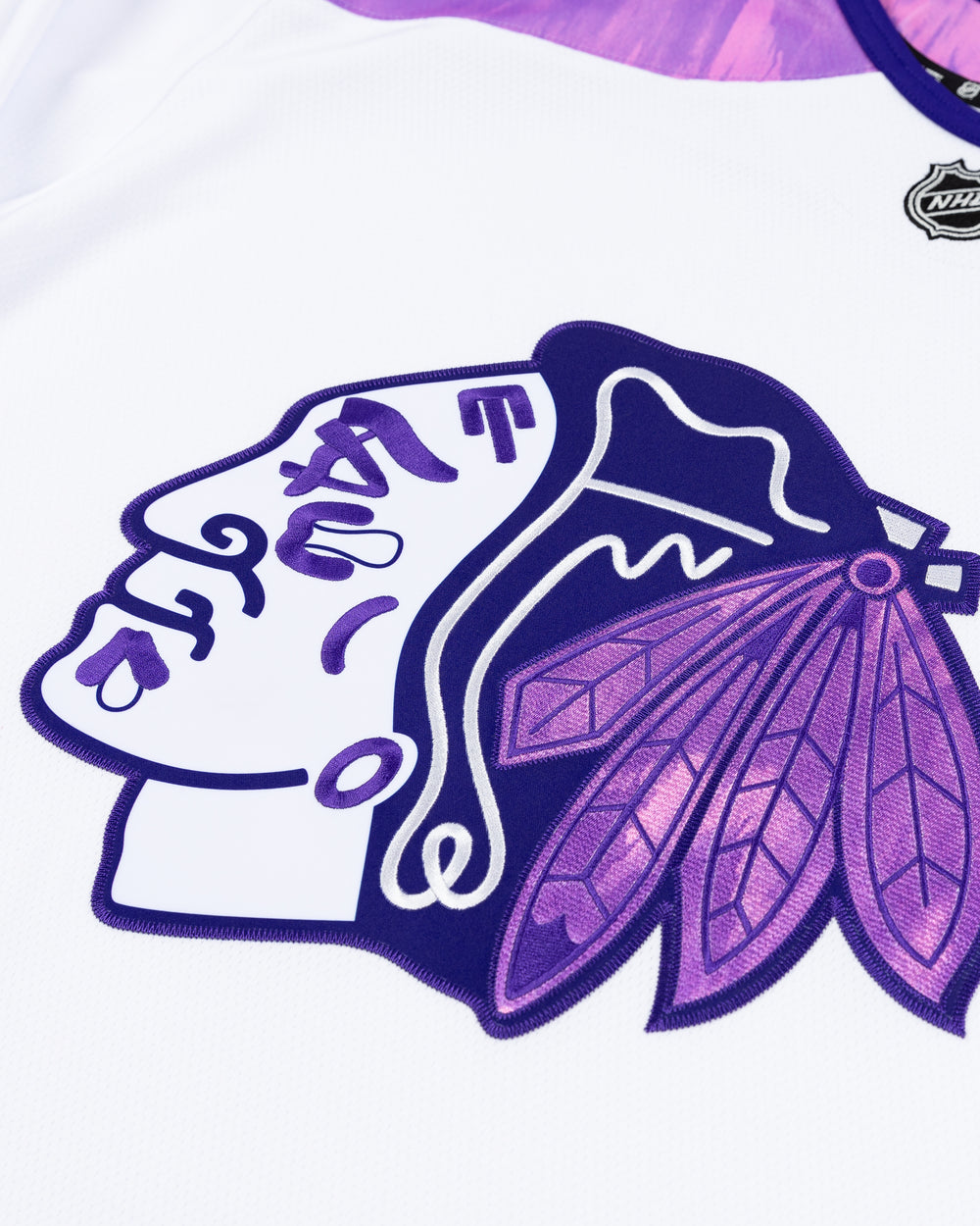 white Fanatics jersey with purple tie dye accents for Hockey Fights Cancer and Chicago Blackhawks tonal primary logo on the front and customizable tag on left hem - front detail lay flat